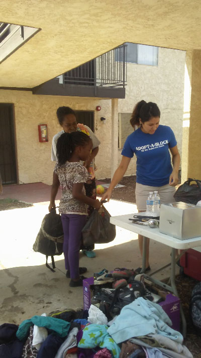 Photo/MJ Duncan Amanda Martinez hands Alon Henderson, who recently suffered a stroke, and her daughter, Shania, 10, two bags filled with groceries on Saturday at the Bella apartment complex on Sierra Way and 44th Street.