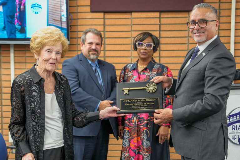 An elderly woman receiving a key to a school district.