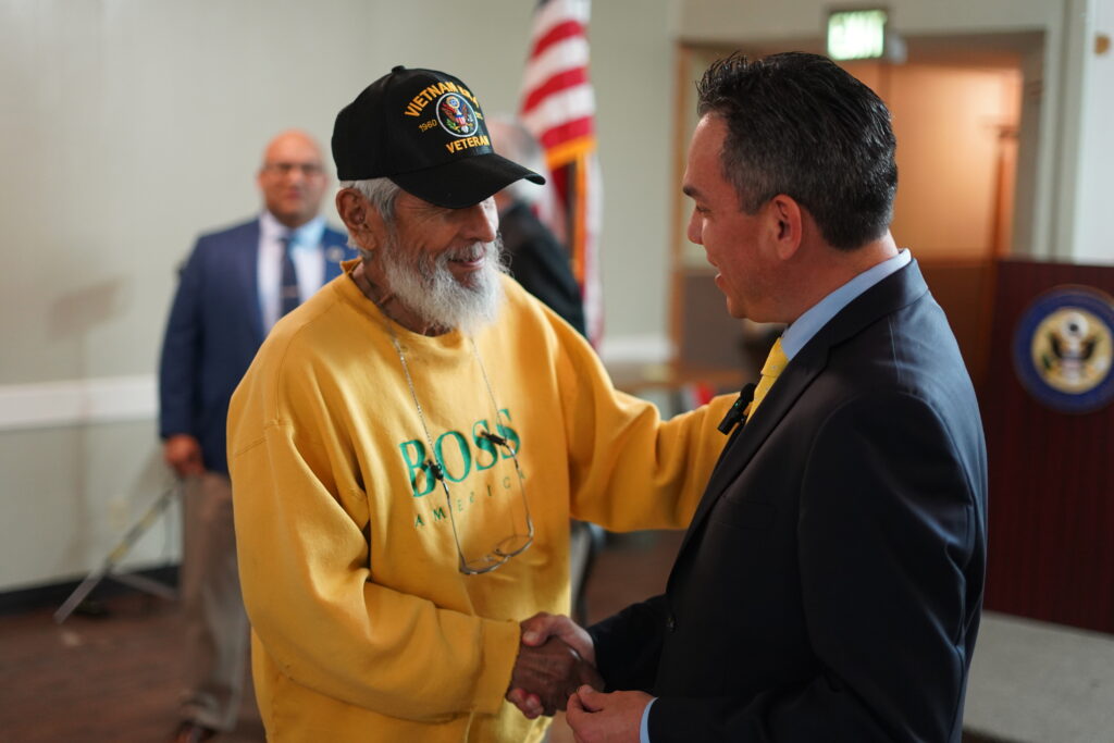A man in a yellow shirt shaking the hand of a man in a blue shirt