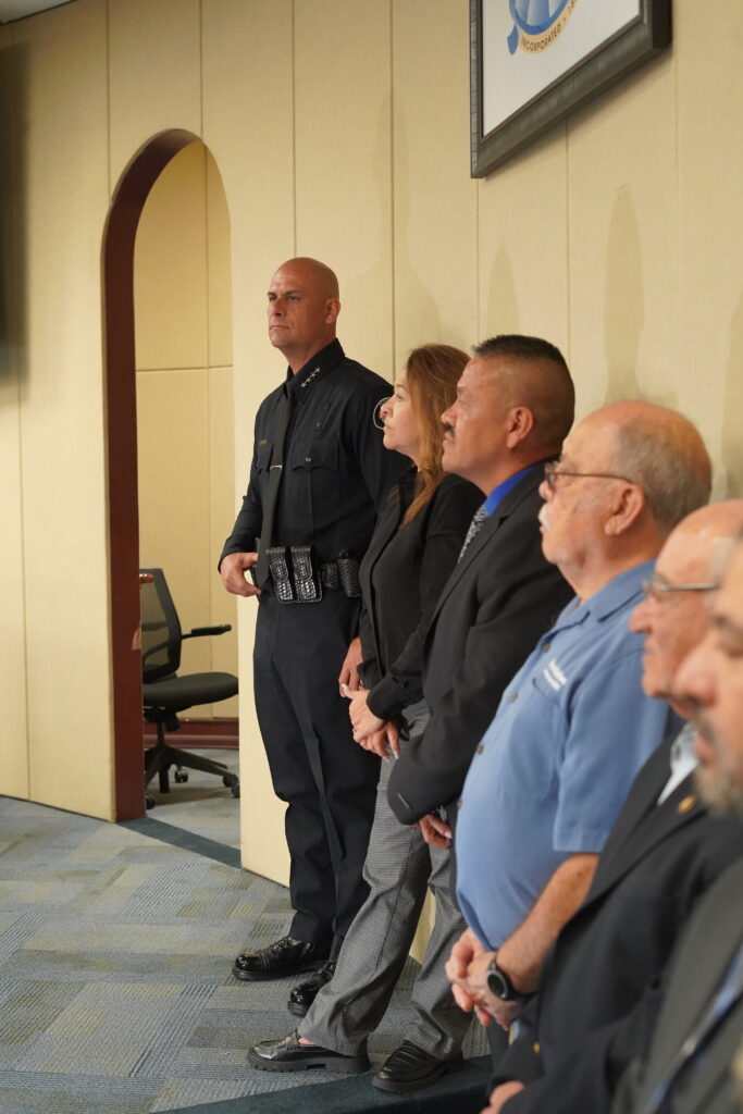 A chief of police standing alongside councilmembers 