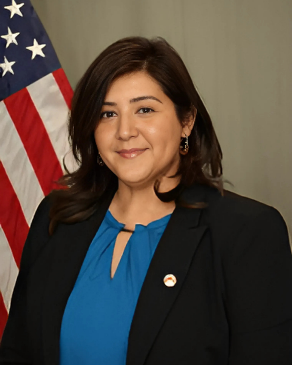 A headshot of a city employee standing in front of a USA flag
